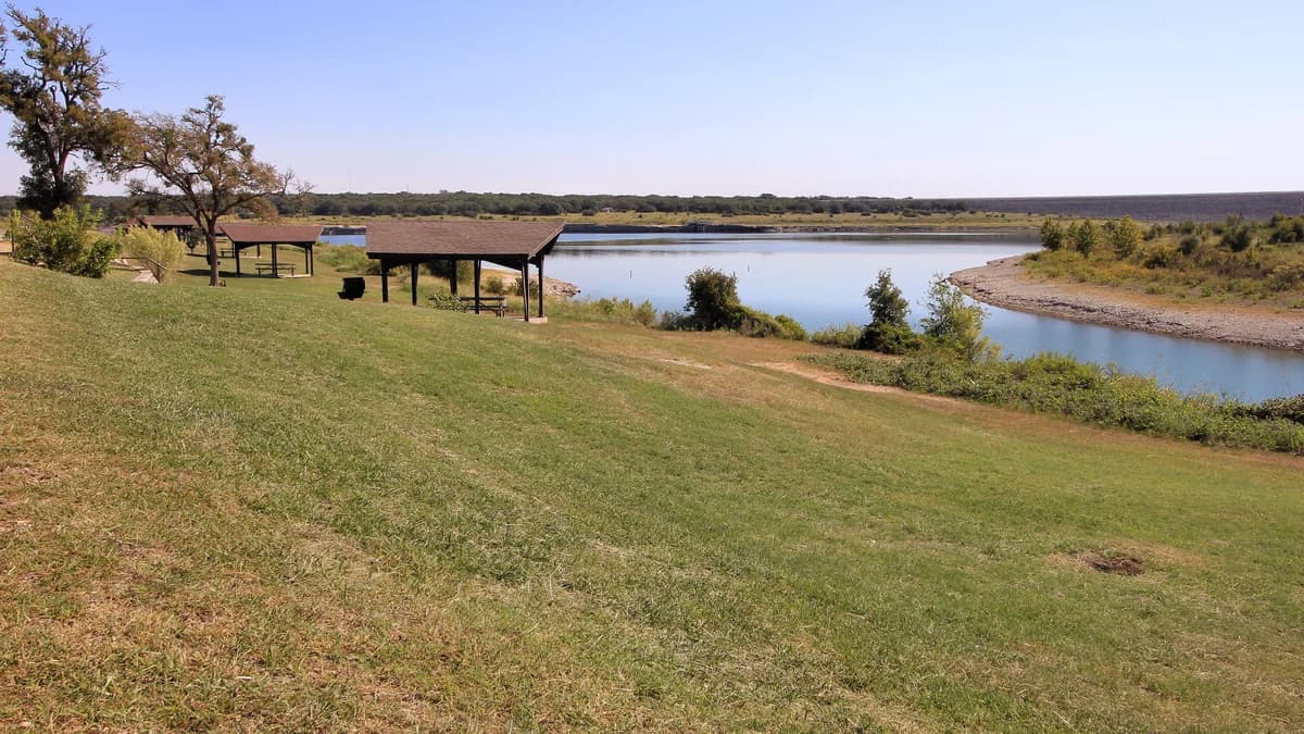 Lake Georgetown on a clear day, picnic pavilions on a mown slope above open blue water